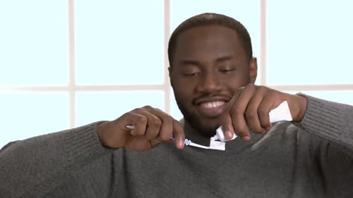 Smiiling Guy Putting on Toothpaste on Toothbrush.