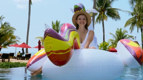 Mulher feliz em trajes de banho divertir-se e relaxar no colchão inflável de unicórnio flutuante