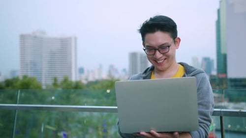 Smiling Young Adult Working on Laptop Outdoors