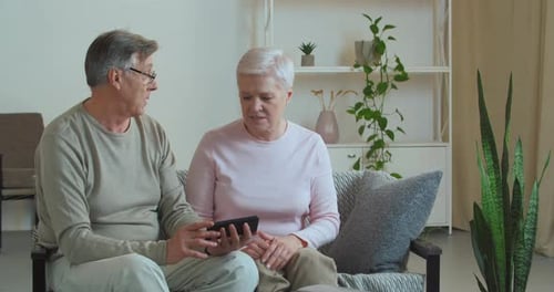 Senior Couple Using Smartphone Together at Home