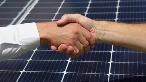 Close Up View of Two Male Engineer Wearing Safety Vest Handshake with Solar Panels Background