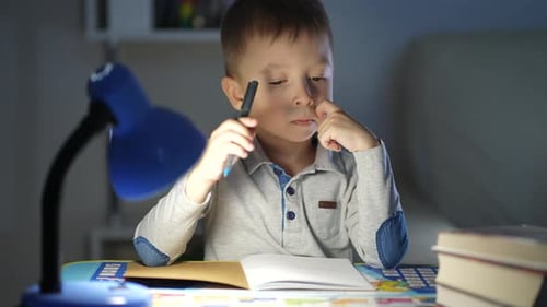 Child Studying Under Lamp at Desk Indoors
