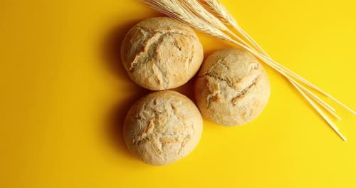 Crusty Bread Rolls with Wheat on Yellow Background