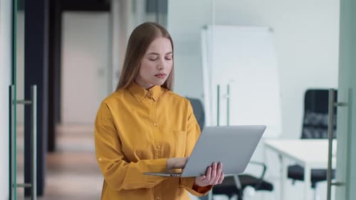 Young Adult Woman Working on Laptop in Modern Office