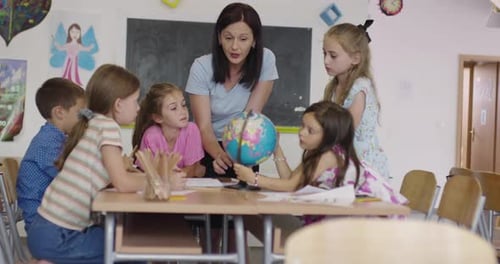 Female Teacher with Kids in Geography Class Looking at Globe