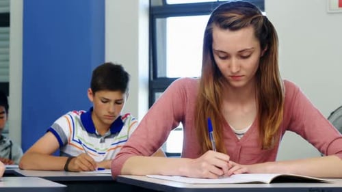 Schoolgirl passing chit to her classmate during exam in classroom