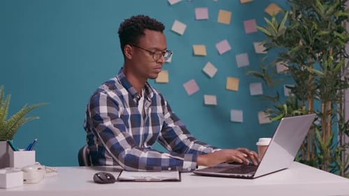 Young Adult Working at Computer in Office Gives Thumbs Up