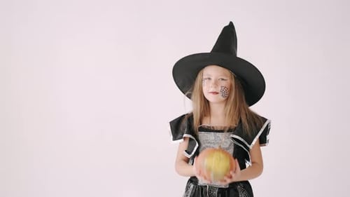 Cute Girl in Witch Costume with Pumpkin