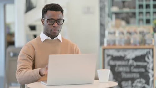 Kreativer afrikanischer Mann schließt Laptop im Stehen und geht weg