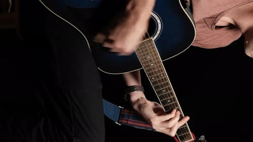 Vertikales Video. Young Man Blogger spielt eine Akustikgitarre auf schwarzem Hintergrund