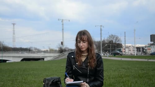 Caucasian Female Student Writing in Exercise Book and Doing Homework in Summer Park