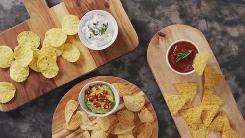 Vista de cerca de una variedad de patatas fritas y salsas en bandejas de madera sobre superficie negra