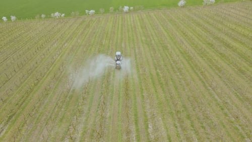 Una vista aérea de un tractor que rocía un cultivo de manzana de los agricultores
