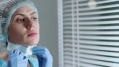 Female Hospital Worker Taking off Mask and Posing for Camera at Work