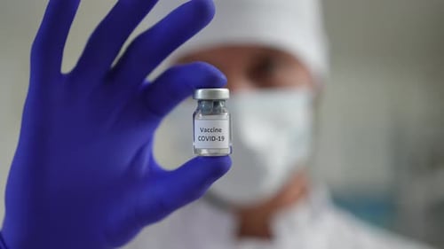 Doctor Holds COVID-19 Vaccine Vial in Blue Gloves