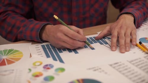 Adult Analyzing Data and Marking Charts with Pencil