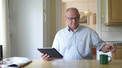 Man Uses Tablet and Drinks Coffee at Home