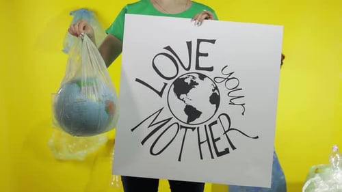 Mujer irreconocible con póster de protesta y globo terráqueo en paquete de plástico. Ecología y contaminación