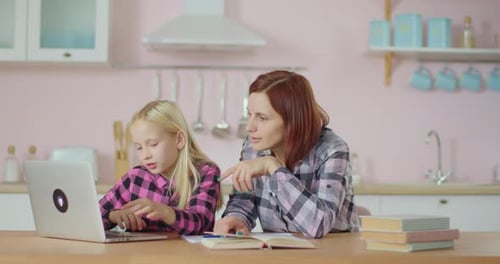 Mother Helping Daughter With Schoolwork at Home