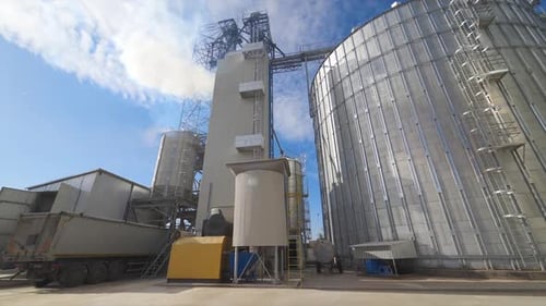 Grain elevators under blue sky. Huge metal grain storage tanks. Silver containers. Close-up.
