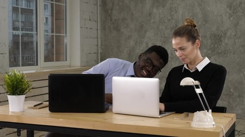 Man and Woman Working Together on Laptop in Office