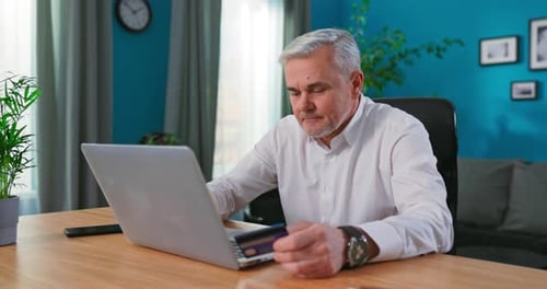 Close Up Elderly Man Sit Indoor Hold Credit Card Make Successful Payment Buy on Internet