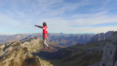 Aerial view of a man balancing while slacklining on a tightrope in the mountains.