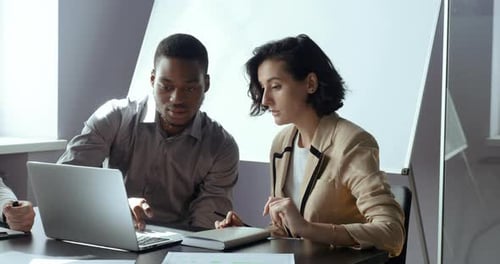 Colleagues Collaborating on Laptop During Office Meeting