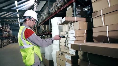 A Warehouse Worker in Protective Equipment Uses a Bar Code Scanner