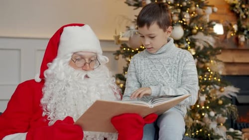 Child Reads with Santa Claus near Christmas Tree