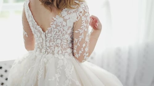 Young bride is dressed for the wedding. Back view of a beautiful, woman in white lace dress.