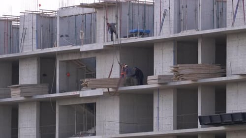 Trabajadores en un sitio de construcción. Una grúa en un sitio de construcción levanta una carga.