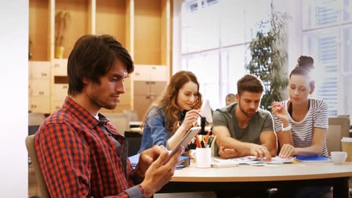 Male business executive using digital tablet while colleagues interacting at desk