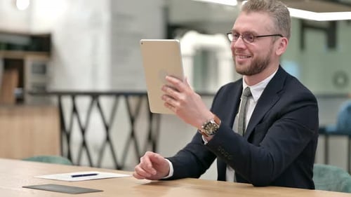 Professional Businessman Doing Video Call on Tablet in Office
