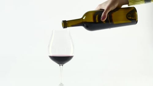 Vin rouge riche versé dans un verre à vin ballon, blanc, au ralenti