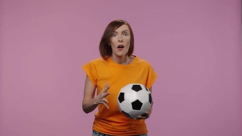 Woman Holds Soccer Ball Gesturing with Excitement