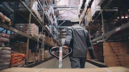 Warehouse Worker Pulling a Pallet Truck, Shooting From Back