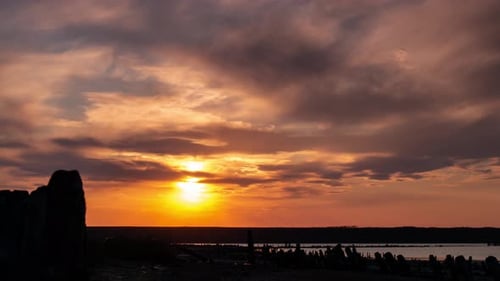 Romantischer bunter Zeitraffer bei Sonnenuntergang auf dem Mündungswasser. Die untergehende Sonne geht über den Berg