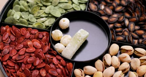 Hand Adding Candied Sweets to Tray of Nuts