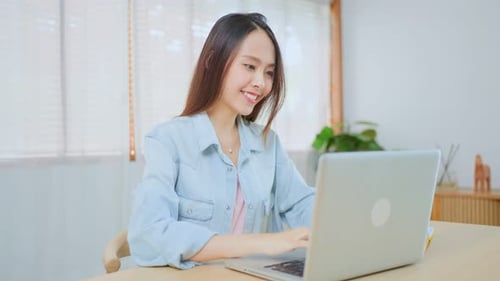 Asian Beautiful school girl use computer study virtual online, watch internet video course at home.