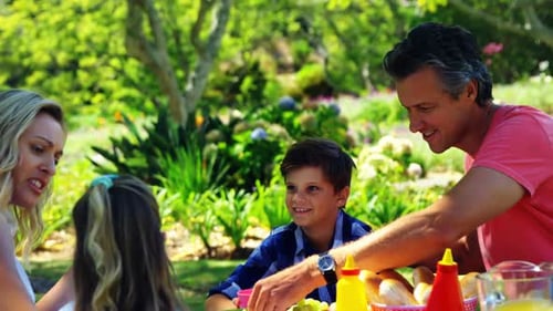 Happy family interacting with each other while having meal in park 4k