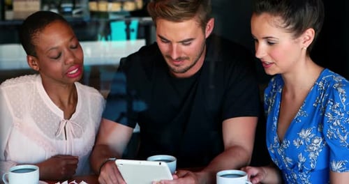 Friends Discussing Ideas on a Tablet in Cafe