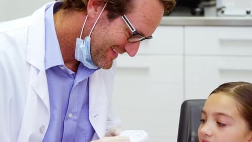 Dentist Showing Teeth Model to Young Child Patient
