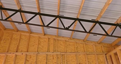 Gebäuderahmen mit Holzbalken und Dachpaneelen auf der Baustelle