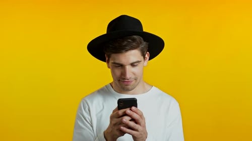 Handsome Hipster Man Texting in Messenger and Receiving Frustrating Sms. Guy Sighs. Yellow Studio