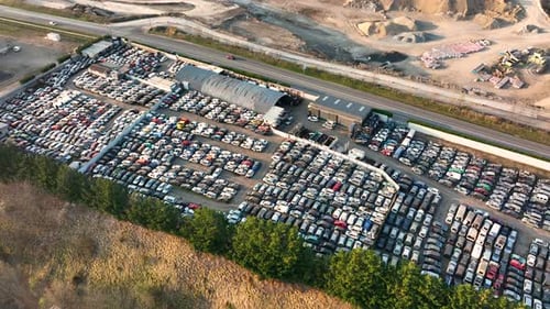 Luftaufnahme des großen Parkplatzes des Schrottplatzes mit Reihen von weggeworfenen kaputten Autos