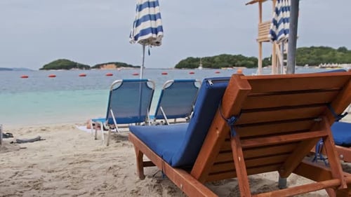 Chaises longues vides sur la plage de sable contre la mer turquoise Albanie Ksamil