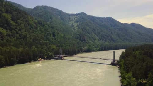 Aerial: Flying Vertically Upwards Over Mountain River, an Automobile Bridge, People Passing Through