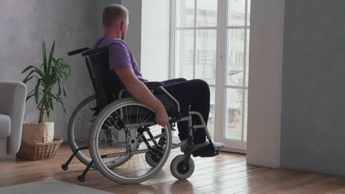 Man in Wheelchair Looking Out Window