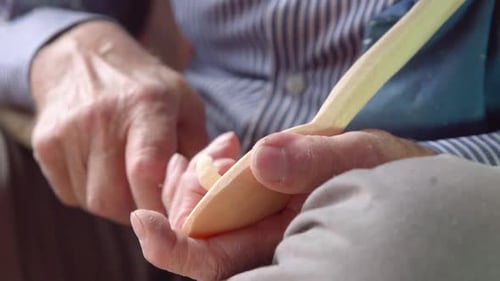 Senior Person Carving Wooden Spoon With Knife